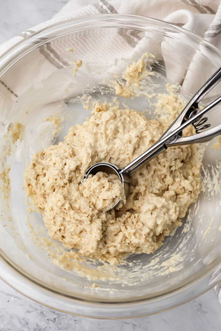 A cookie scoop measuring out dough to make donut holes.