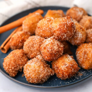 A blue plate filled with vegan cinnamon and sugar donut holes.