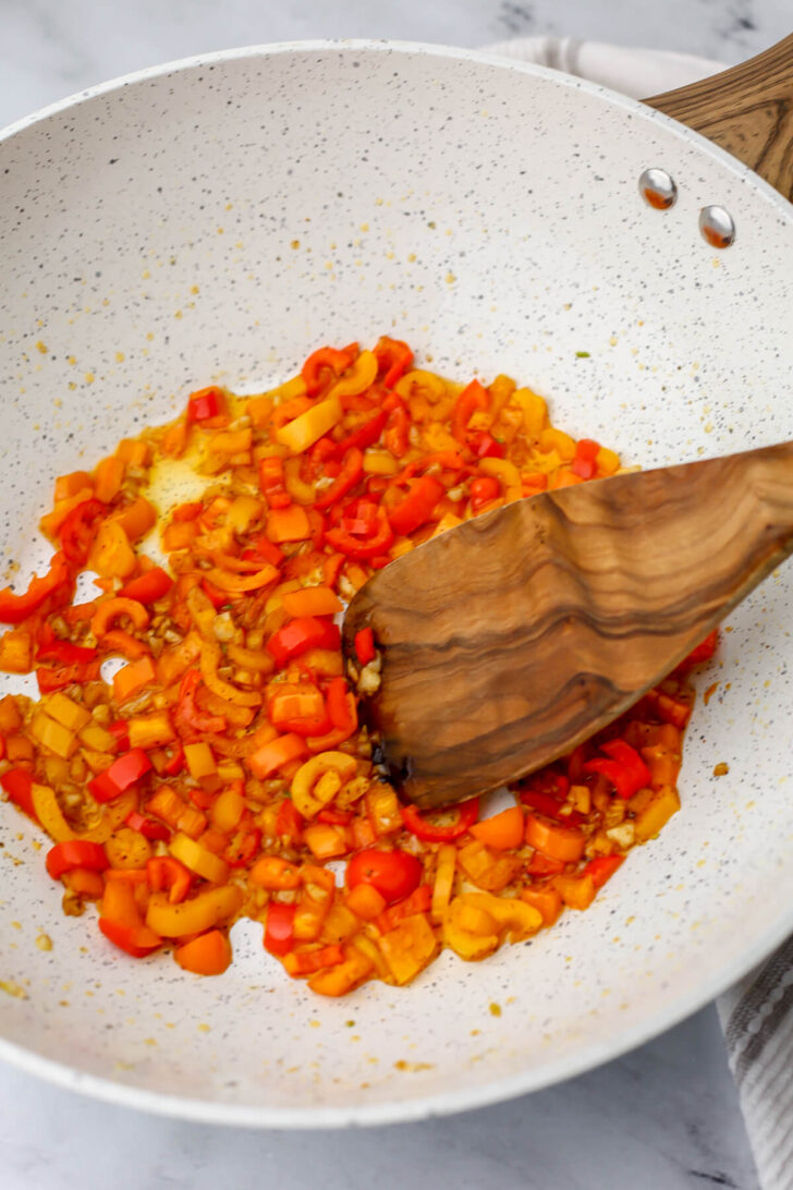 Garlic and bell peppers sauteing in a skillet.