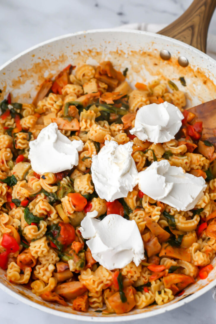 Vegan sour cream being added to vegan chicken Cajun pasta.