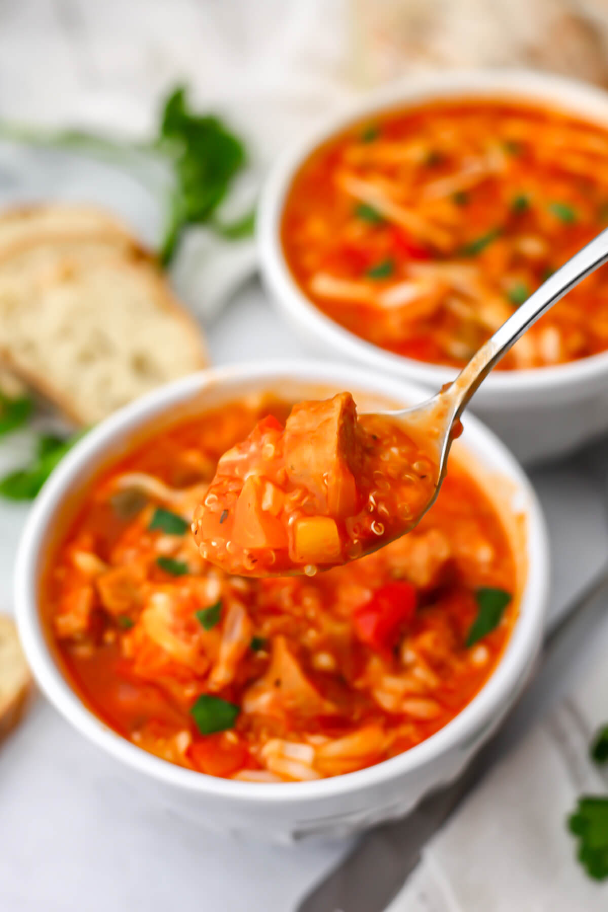 A close up of a spoonful of vegan stuffed pepper soup with quinoa and vegan sausage.