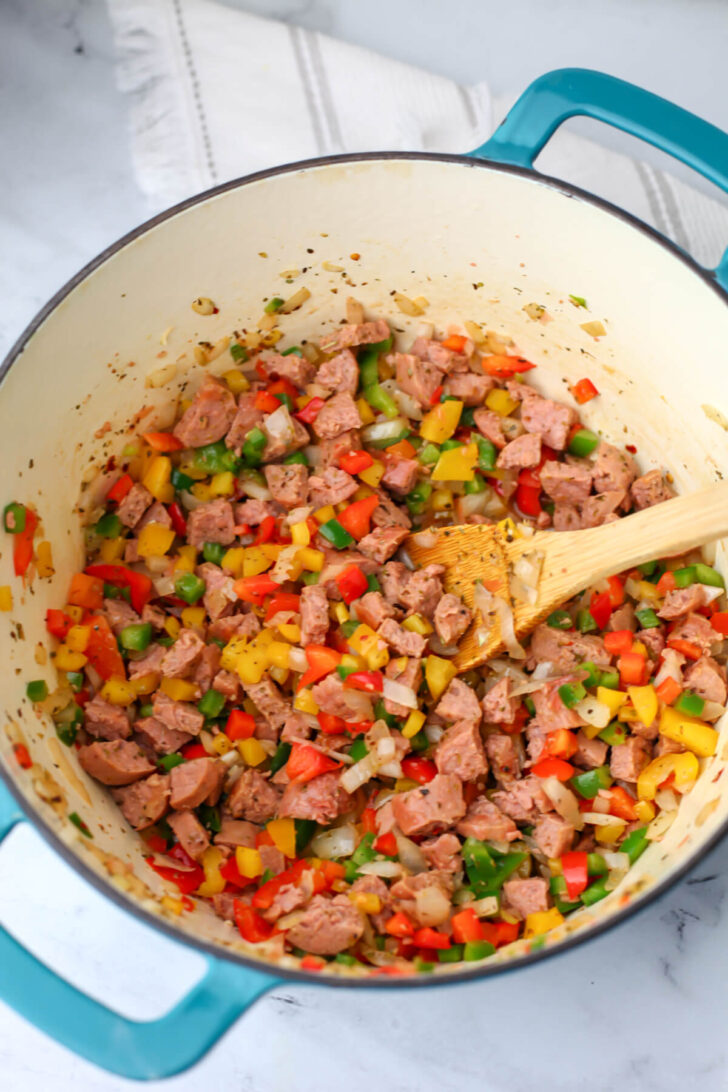 Onions, peppers, and vegan sausage sautéing in a soup pot.