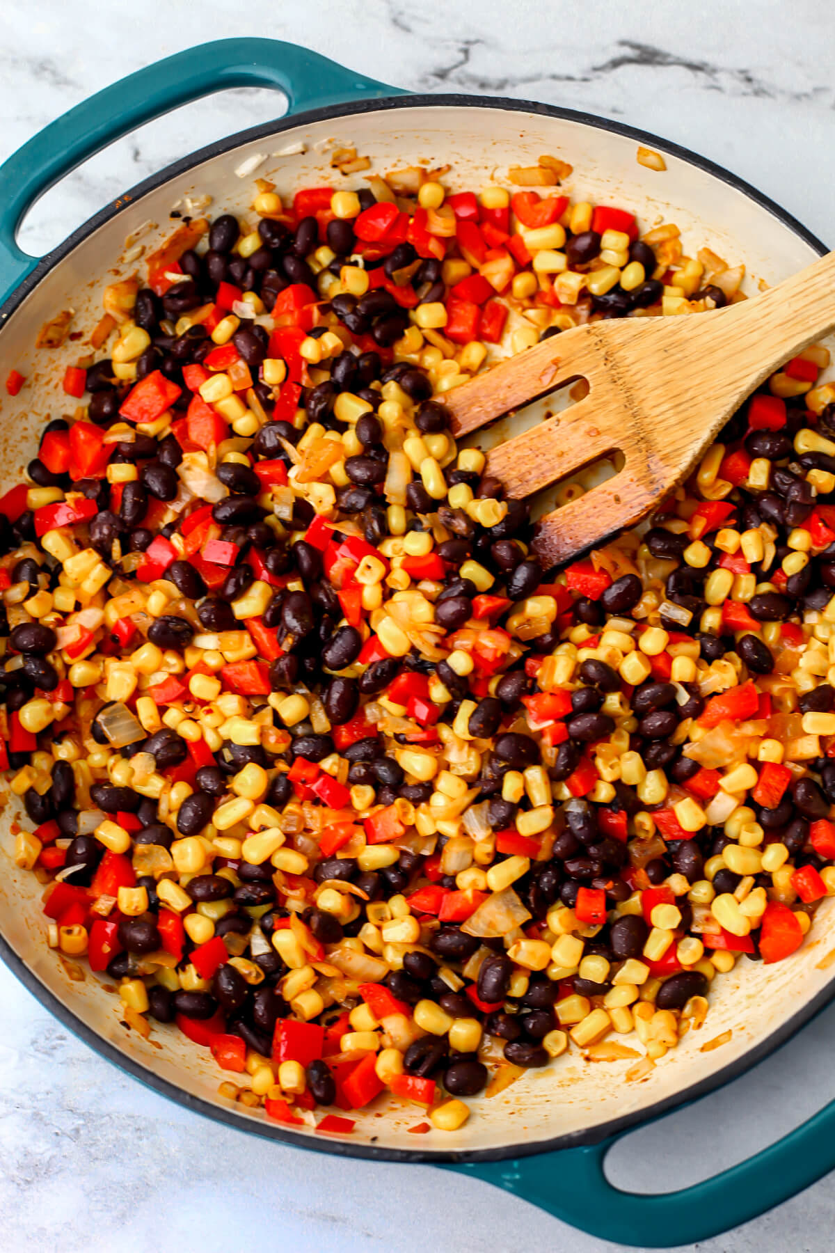 Onions, red pepper, black beans, and corn sauteing in a skillet.