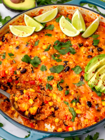A skillet filled with vegan Mexican quinoa topped with cilantro, lime slices, and avacado.