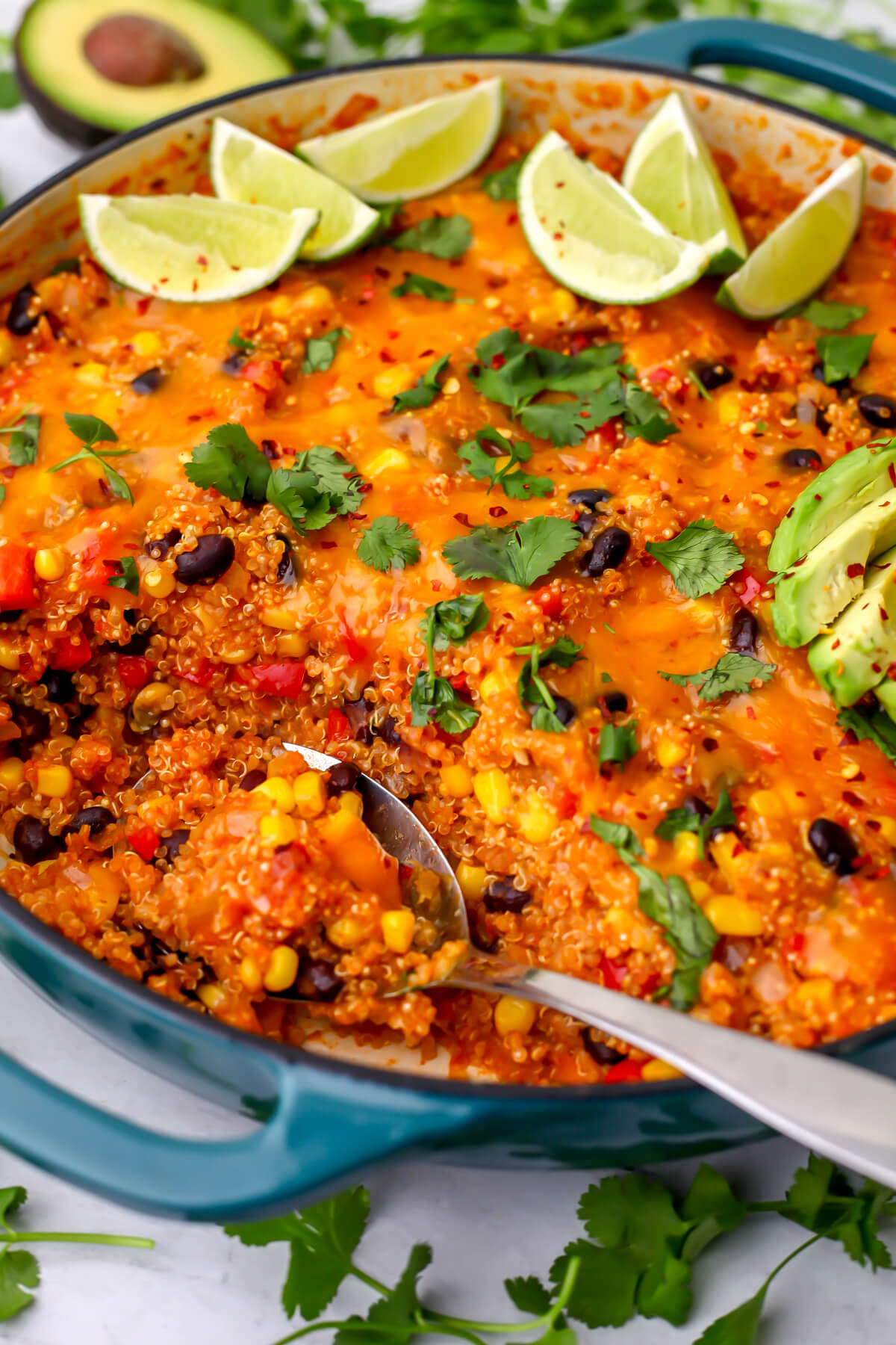 A spoon scooping out vegan Mexican quinoa out of a blue skillet.