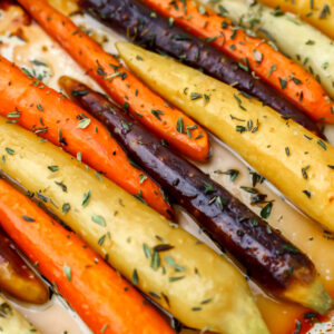 A closeup of roasted rainbow carrots with agave glaze and thyme.