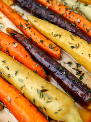 A closeup of roasted rainbow carrots with agave glaze and thyme.