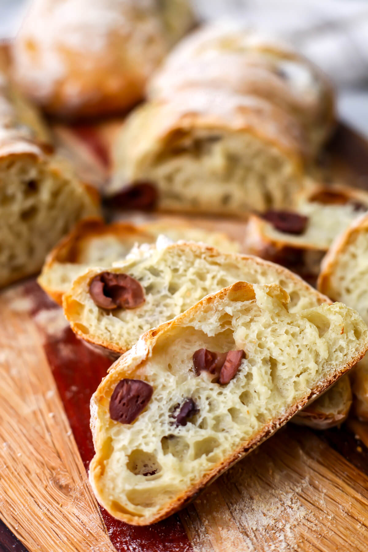 Vegan olive bread cut into slices on a wooden cutting board.