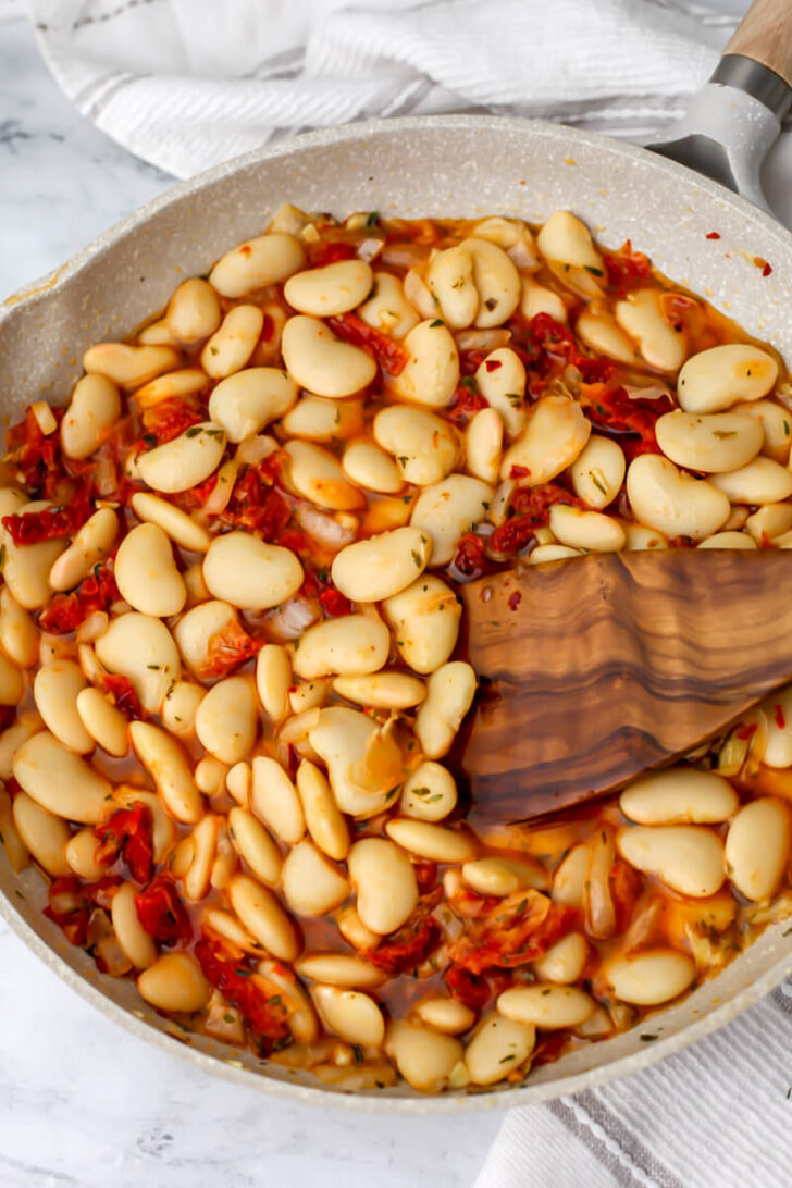 Broth and sundried tomatoes added to butter beans.