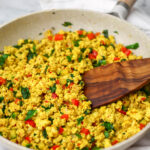 A skillet full of Tofu Bhurji made with Indian curry and diced zucchini, red peppers, and spinach.