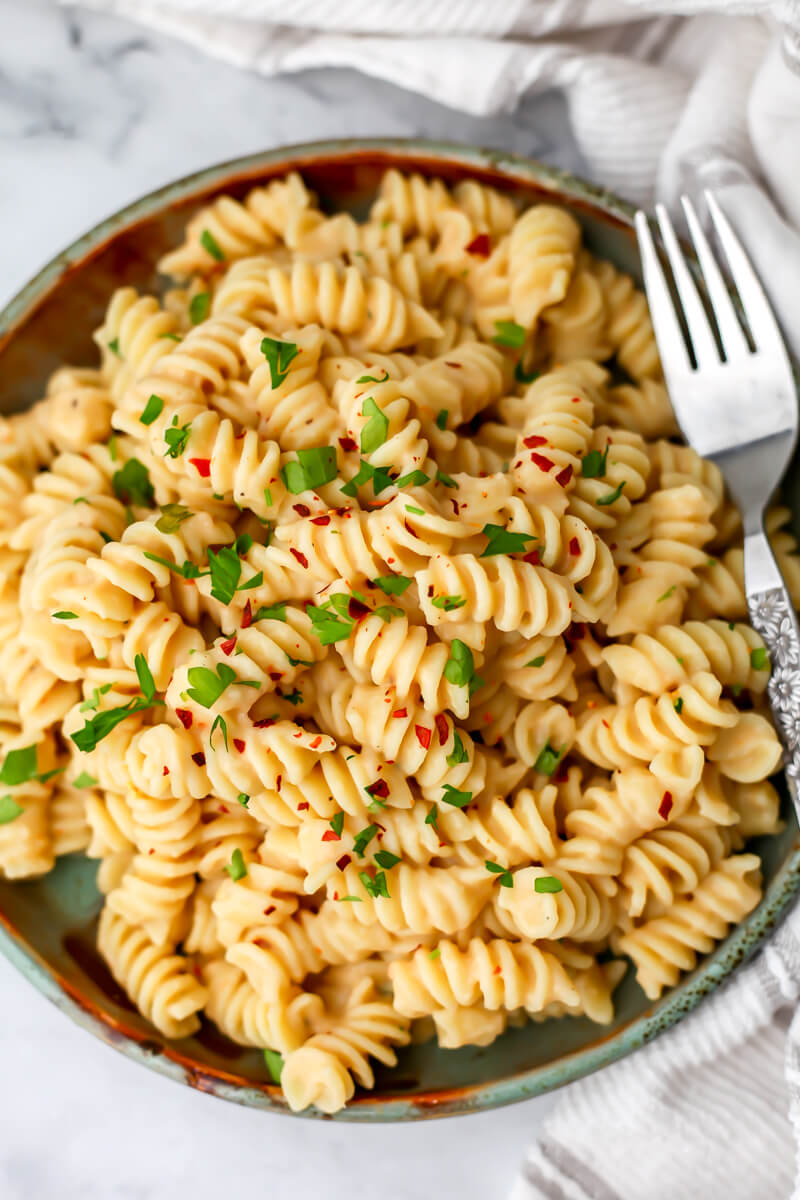 A top view of a plate of creamy white bean pasta with a fork on the side.