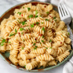 Creamy vegan white bean pasta sauce with spiral noodles on a green plate.