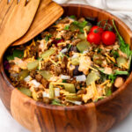 A vegan Big Mac salad in a wooden salad bowl topped with pickles, onions, and Big Mac sauce.