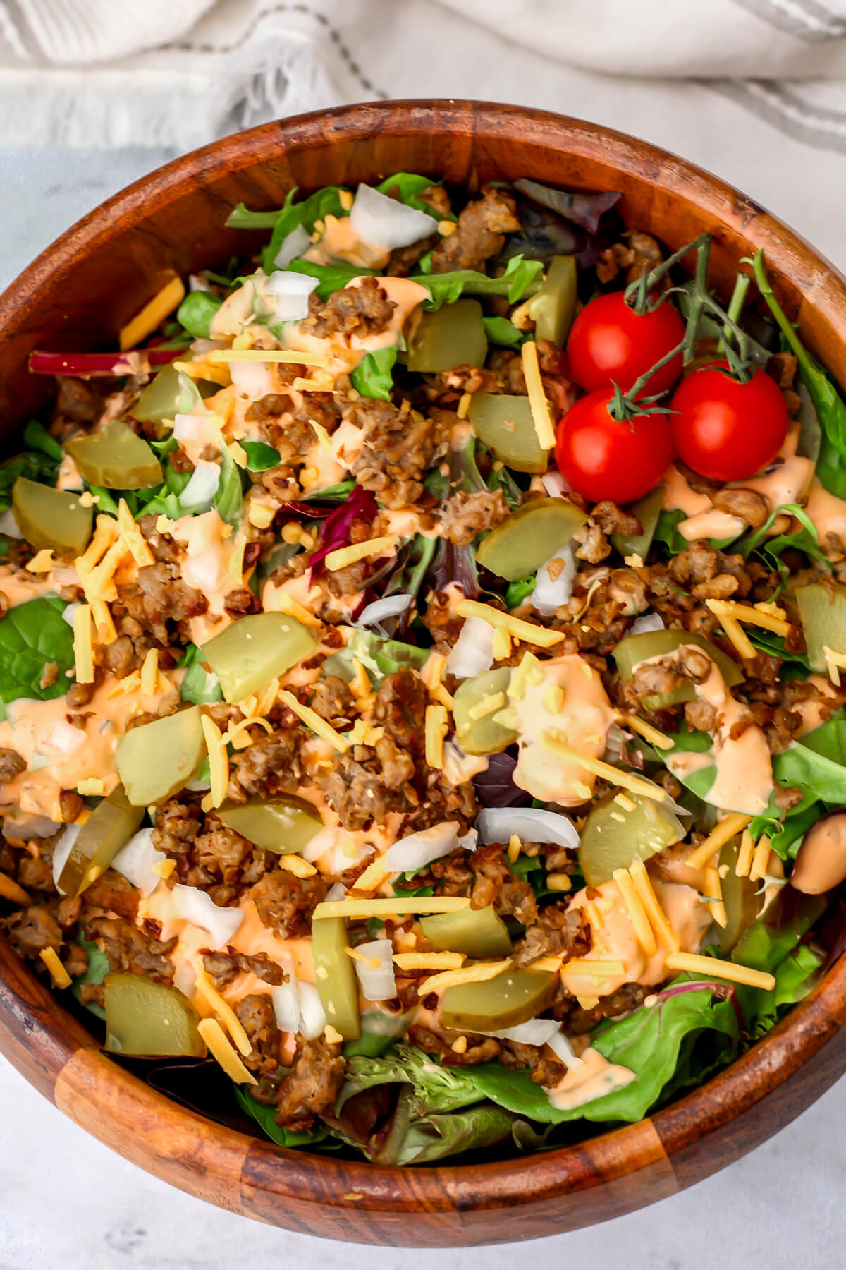 A top view of a vegan Big Mac salad in a wooden salad bowl.