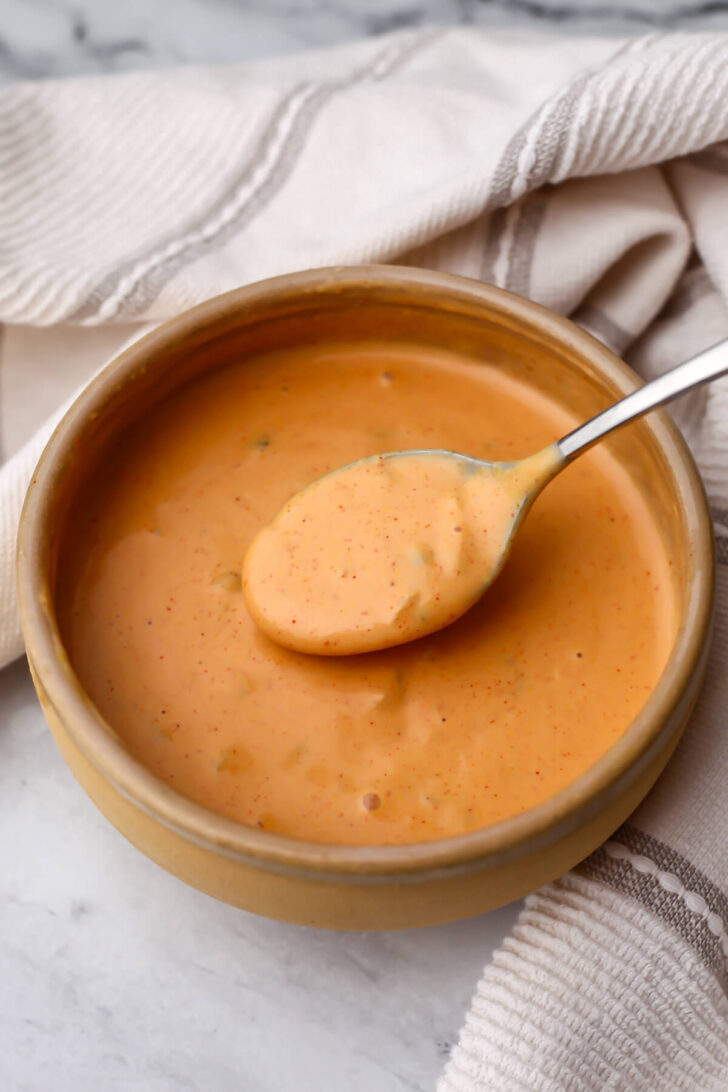 Vegan Big Mac sauce stirred together in a bowl with a spoon in it.