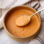 A bowl of vegan Big Mac sauce with a spoon scooping some up.