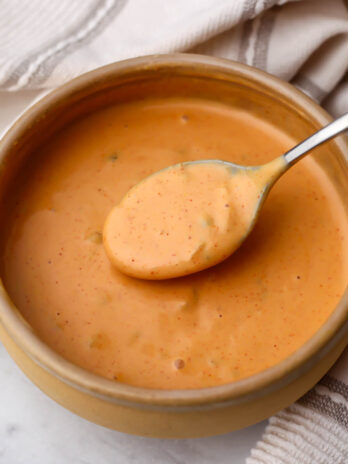 A bowl of vegan Big Mac sauce with a spoon scooping some up.