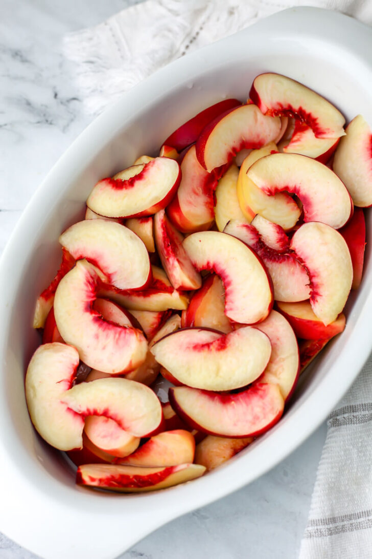 Sliced peaches in a baking dish.
