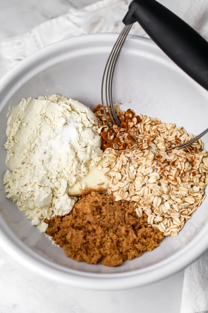 Flour, butter, brown sugar, and oats in a bowl to make a crumble topping.