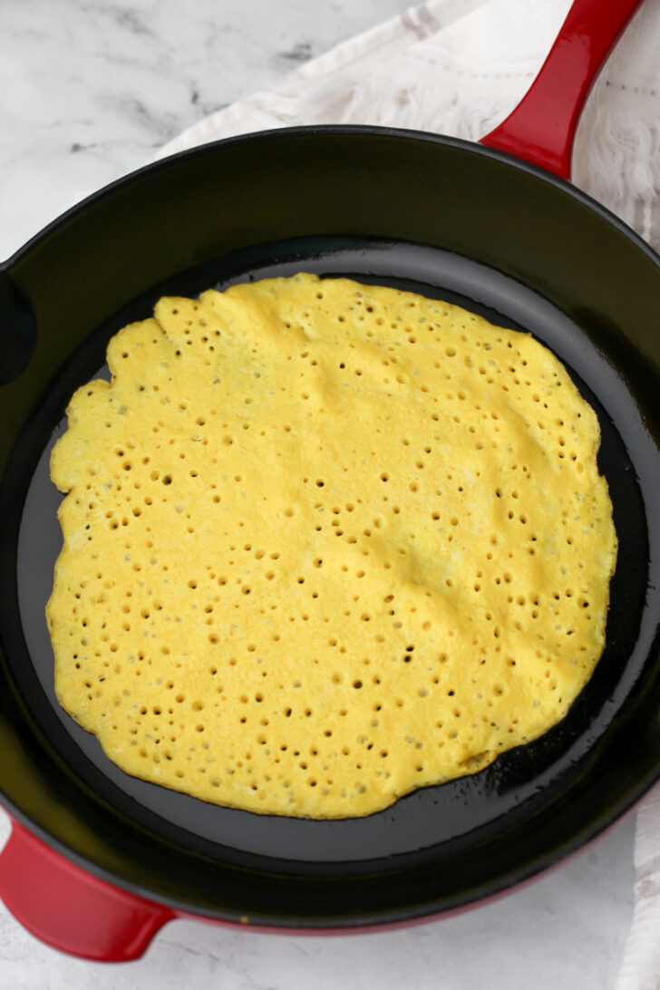 Just Egg batter frying in an iron skillet.