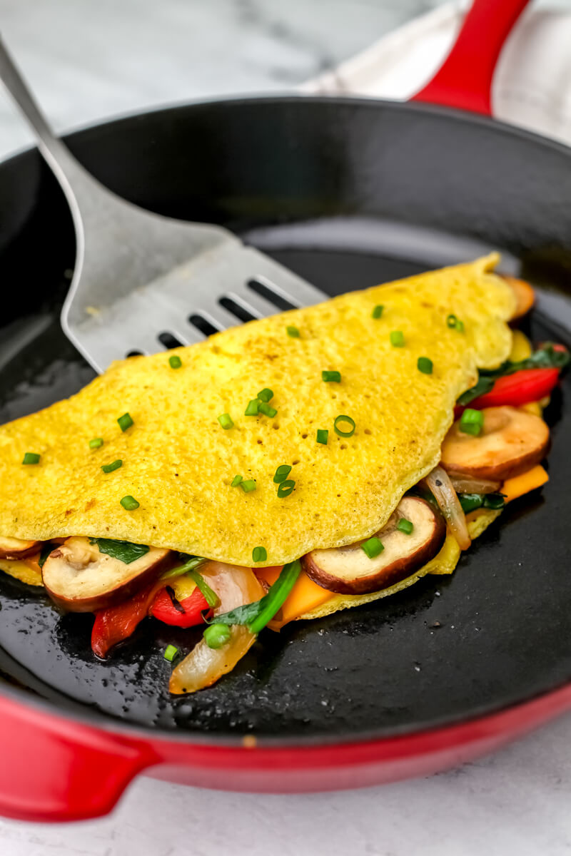A vegan just egg omelette filled with sautéed veggies in a red iron skillet.