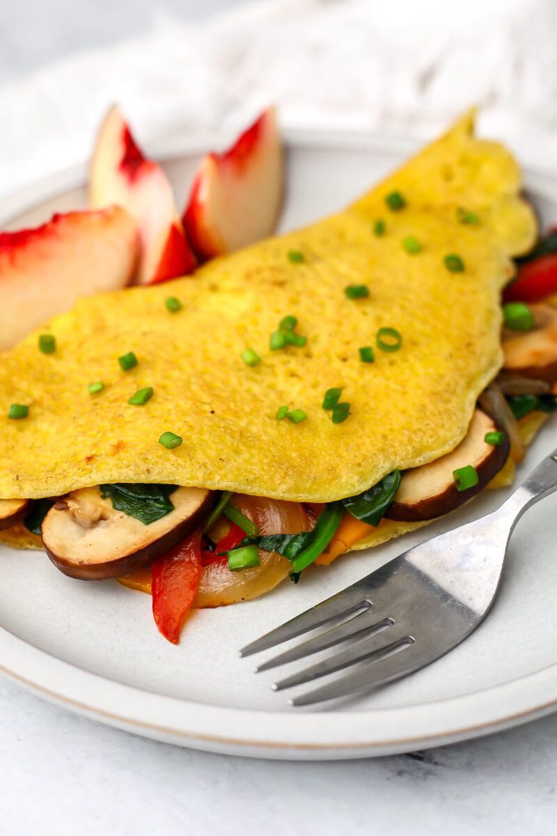 A vegan Just Egg omelet on a white plate filled with veggies.