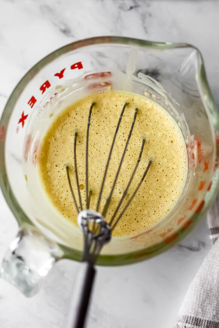 Vegan omelet batter stirring in a glass measuring cup.