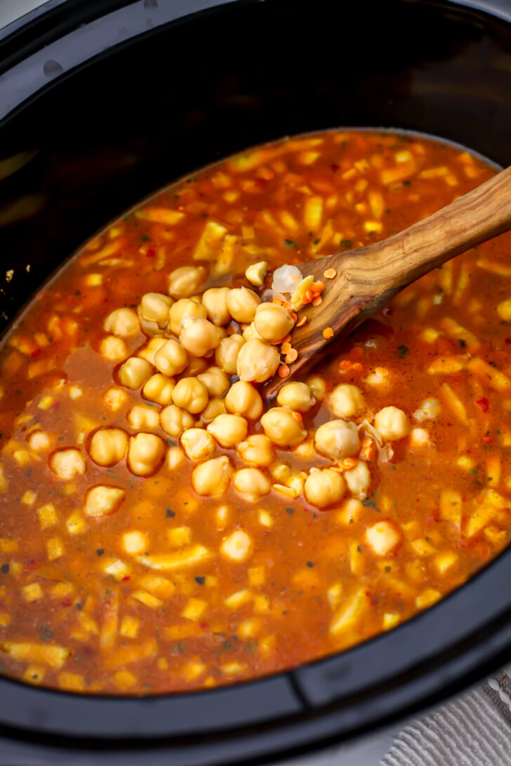 Red lentils, tomatoes, and chickpeas added to the spices in a slow cooker to make red lentil dahl.