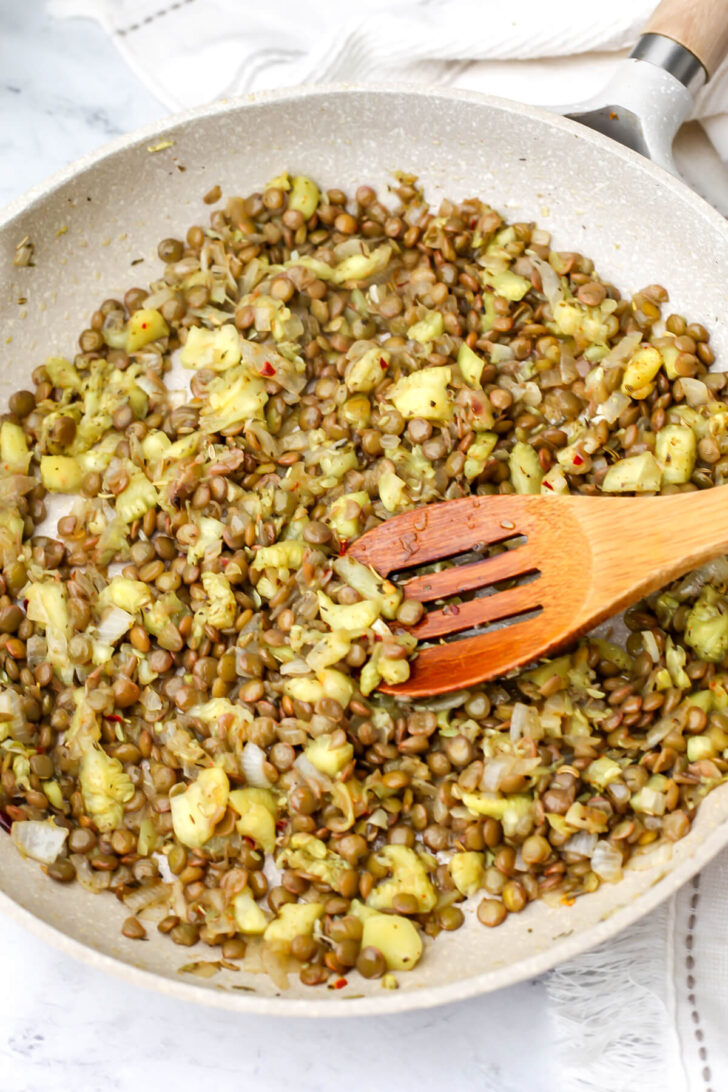 Lentils added the the onions and zucchini in a frying pan.
