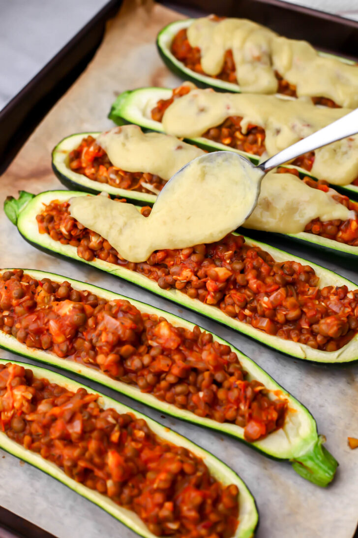 Topping the vegan zucchini boats with vegan pizza cheese sauce.