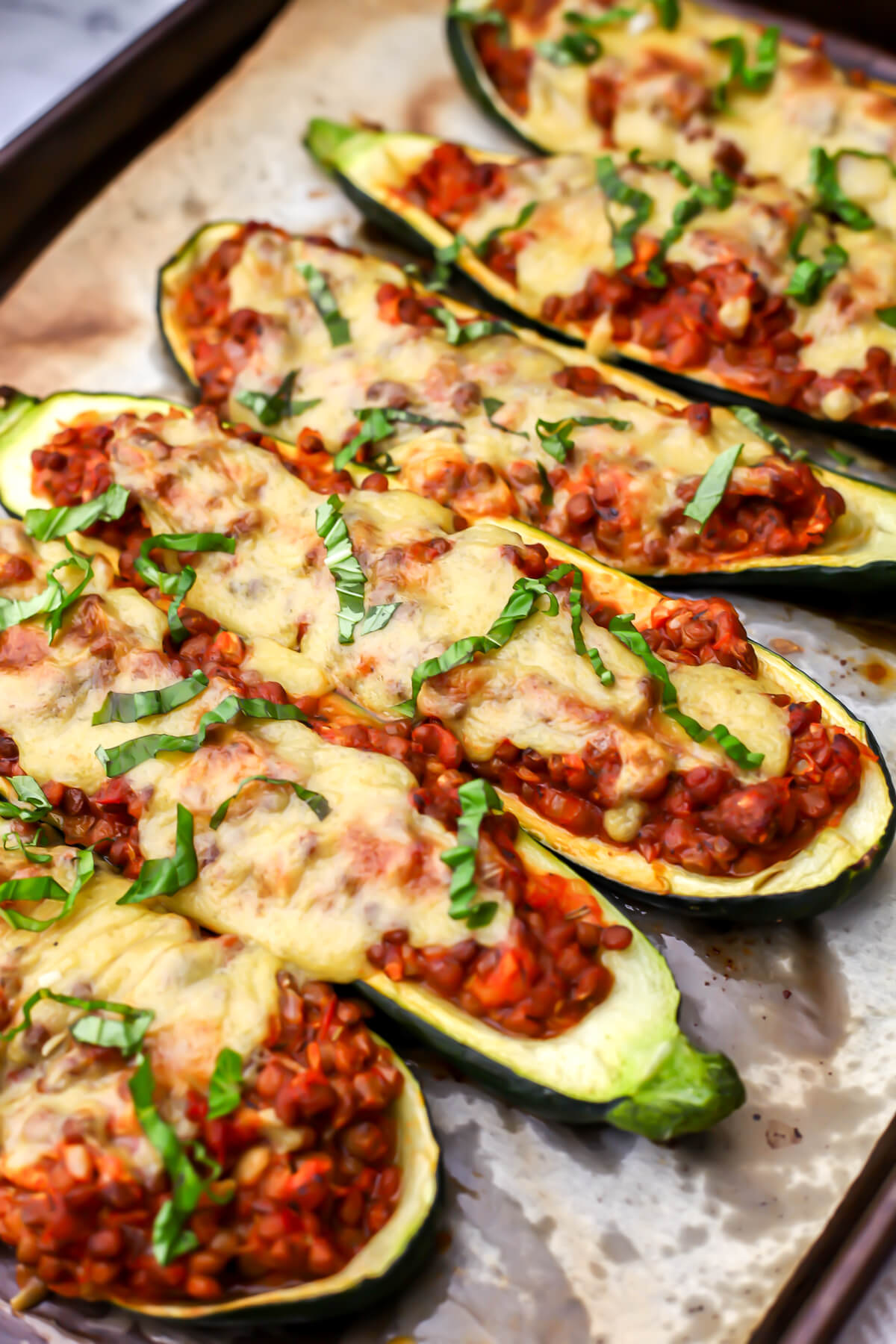 Vegan zucchini boats on a parchment lined cookie sheet.