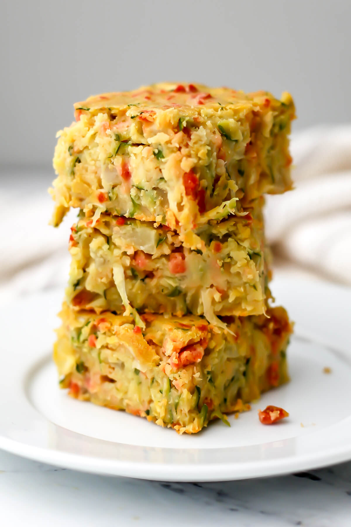 Three pieces of vegan zucchini slice on a white plate.