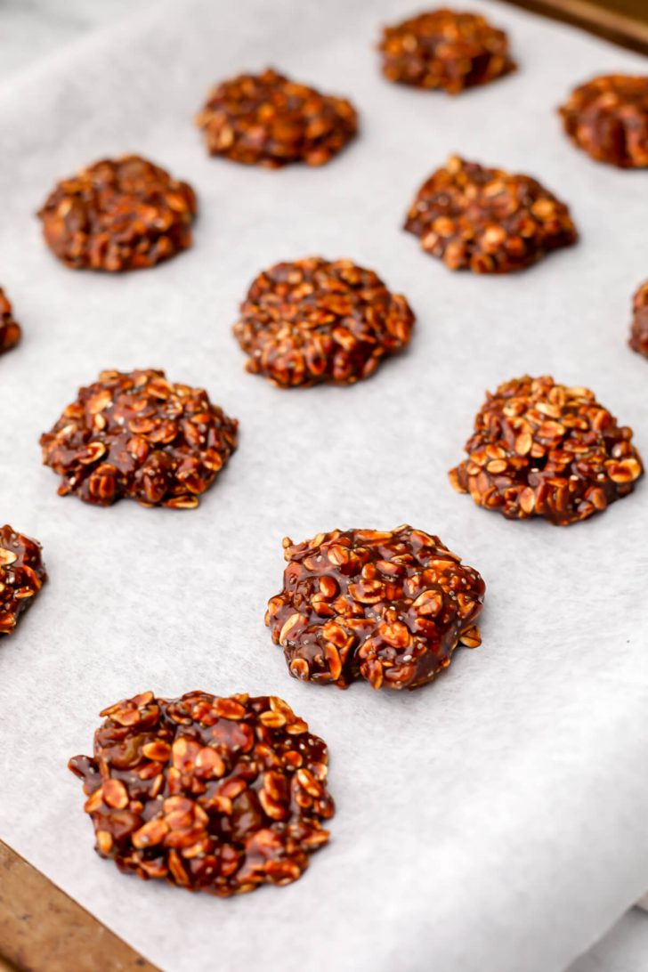 Almond butter no-bake cookies on parchment paper on a cookie sheet.