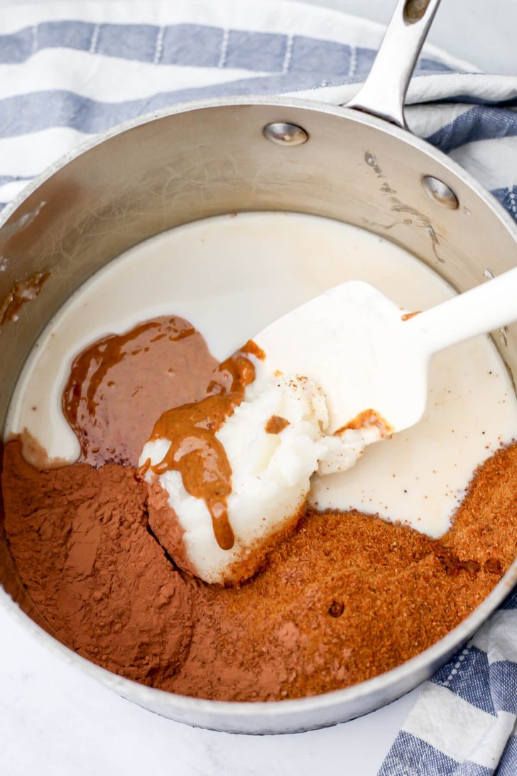 Almond butter, coconut oil, cocoa powder, and almond milk in a sauce pan to make no-bake cookies.
