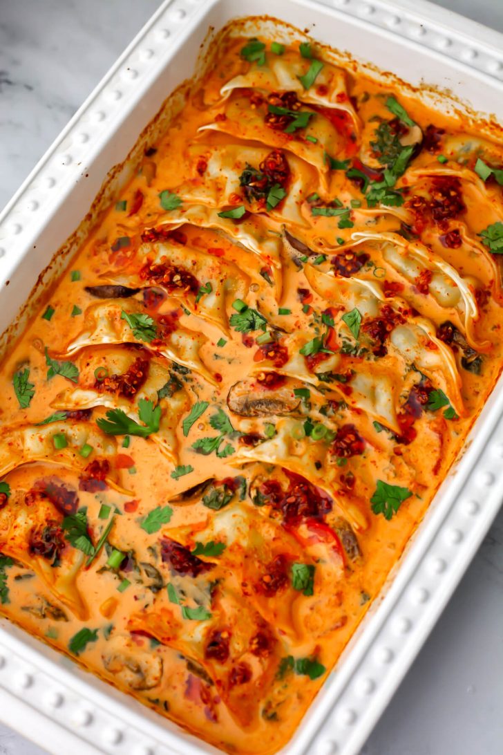 Vegan baked dumplings garnished with fresh cilantro, green onions, and crunchy chili onion oil.