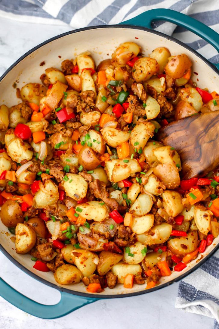 A top view of a vegan breakfast hash recipe made with onions, peppers, vegan breakfast sausage, and potatoes.
