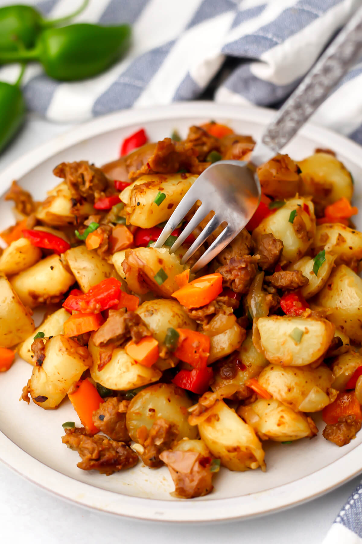 Vegan breakfast hash on a white plate with a fork in it.