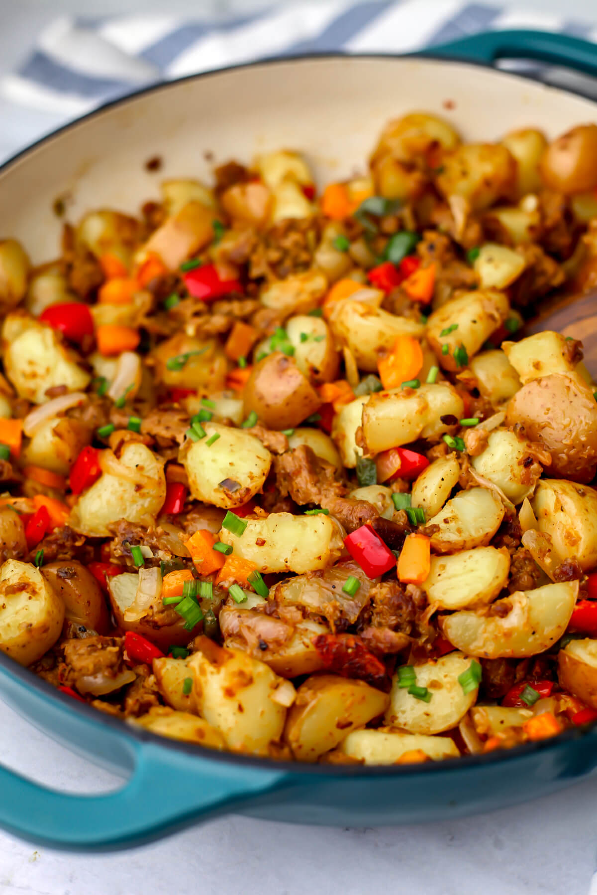 Vegan hash with vegan breakfast sausage, peppers, onions, and potatoes in a blue skillet.