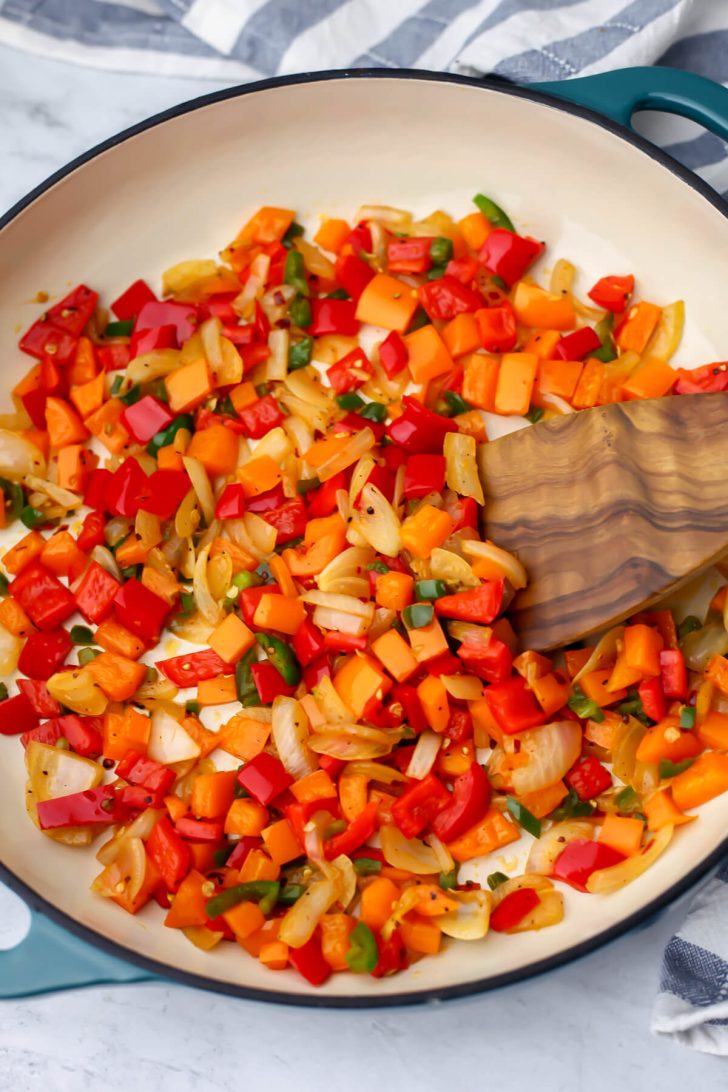 Onions and peppers sautéing in a skillet.