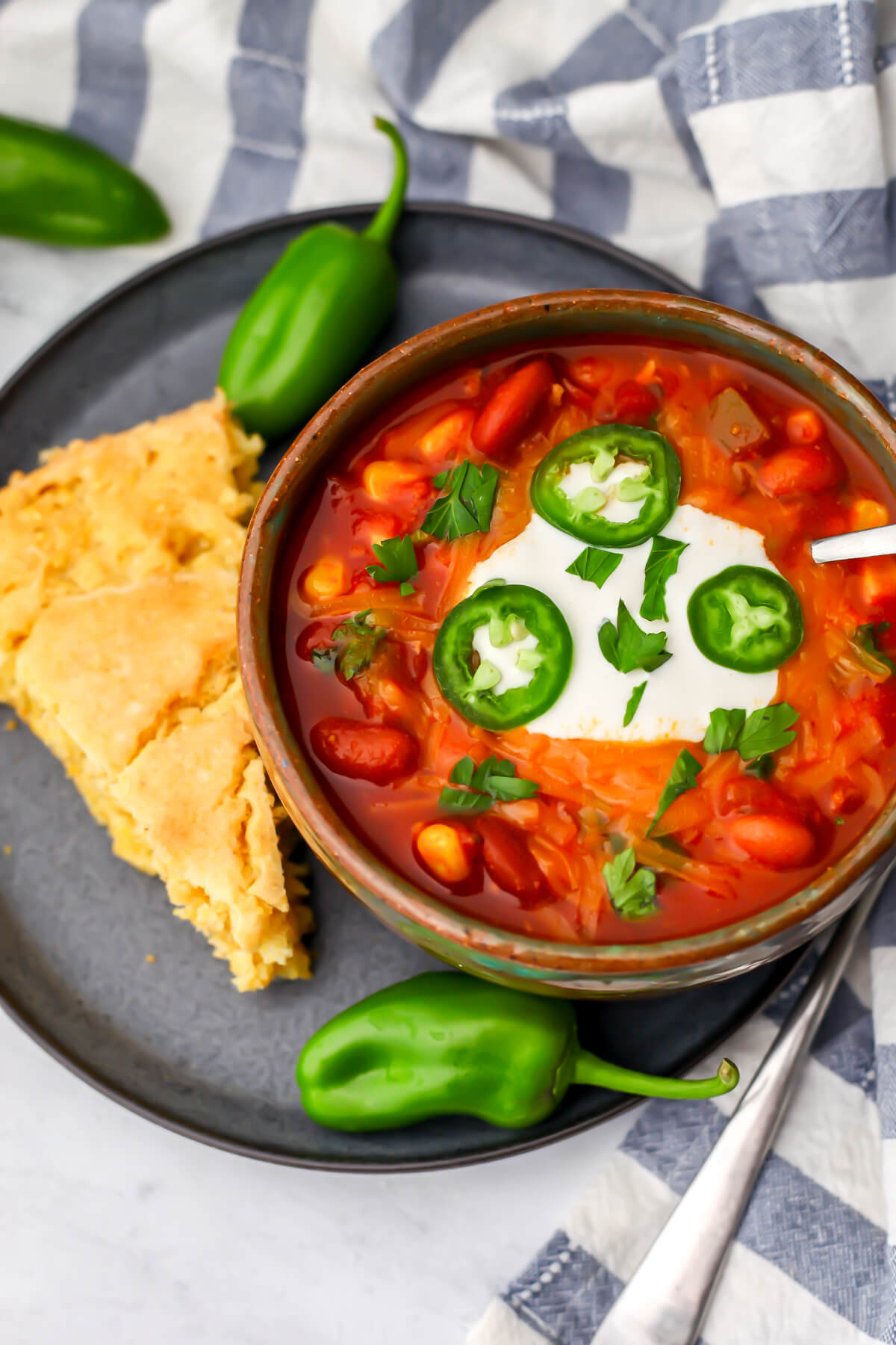 A top view of a bowl of vegan chili with a piece of cornbread on the side.