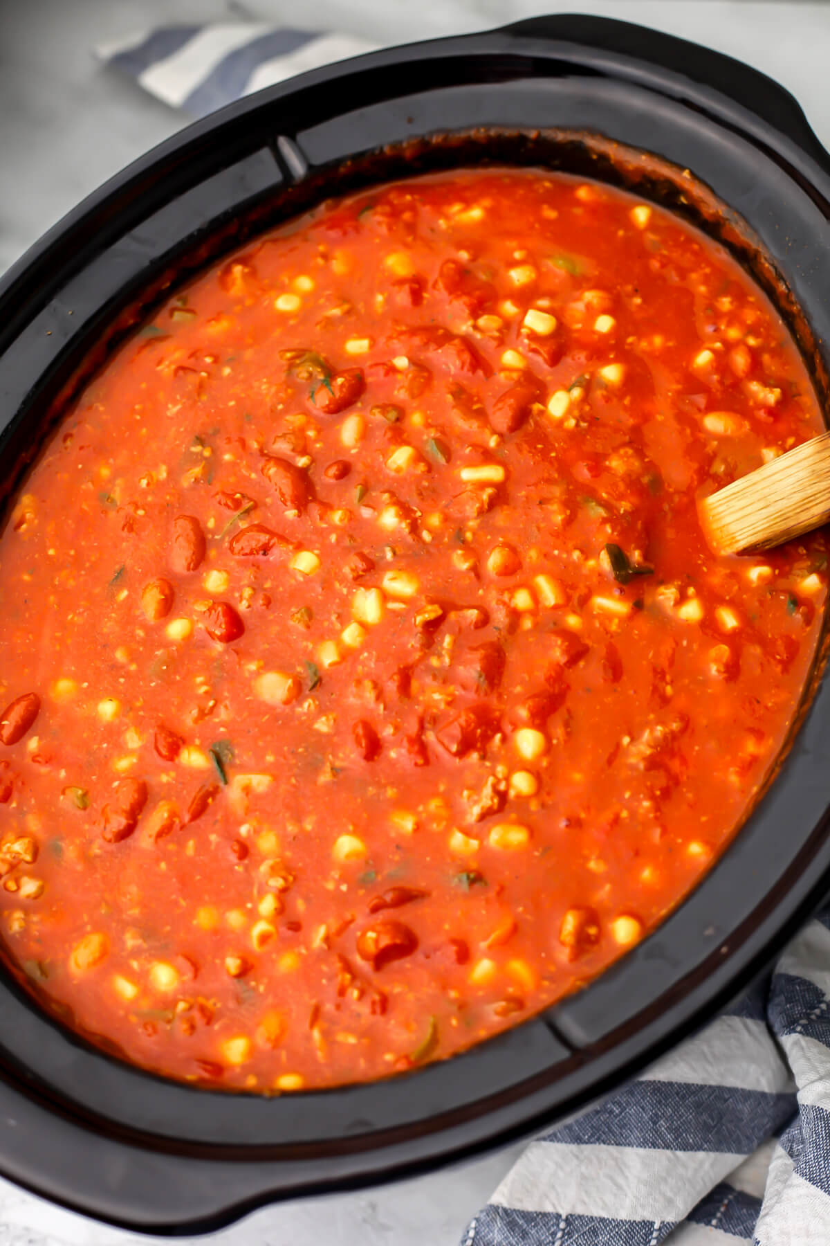 A top view of all of the vegan chili ingredients added to a slow cooker before cooking.