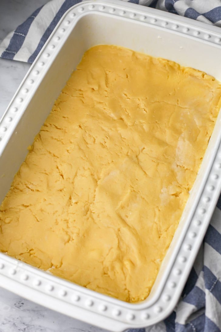 A mixture of cake mix and butter pressed to the bottom of a baking dish as the first layer of pumpkin pie cake.