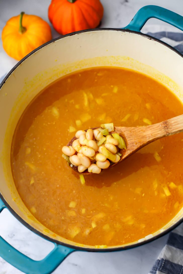 Vegetable broth and pumpkin puree added to the white beans to make soup.