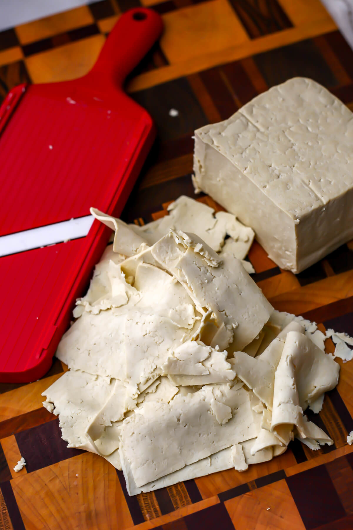 High-protein tofu sliced with a mandoline on a cutting board.