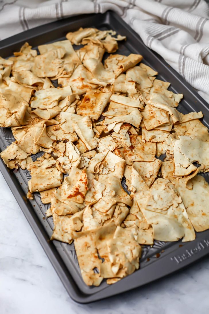 Marinaded shaved tofu spread out on a sheet pan before cooking to make tofu deli meat.