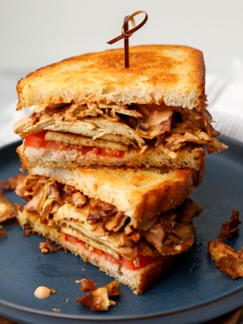 A grilled tofu sandwich made with shaved tofu on a blue plate.