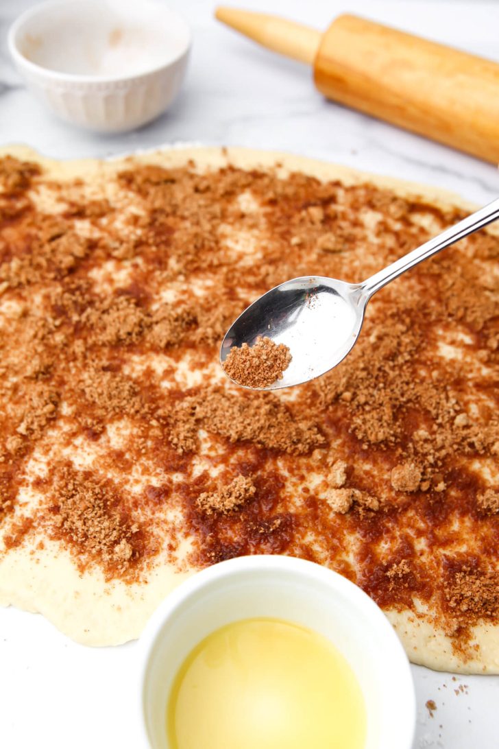 Sprinkling cinnamon and brown sugar on the dough.