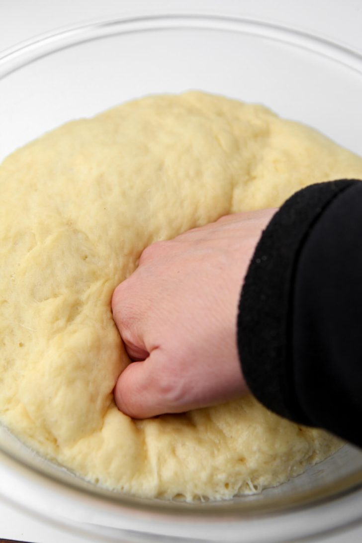 Punching down the sticky bun dough after it rises.