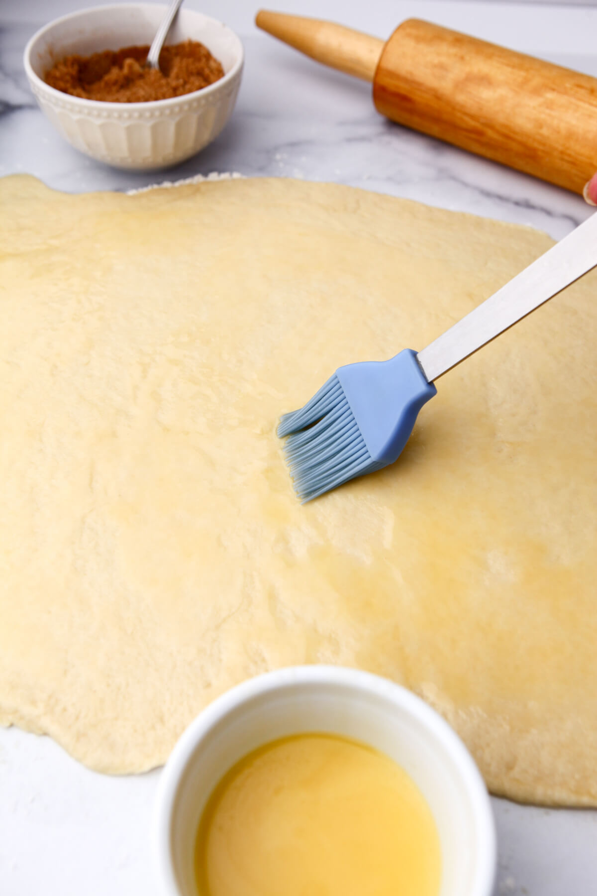 Spreading melted butter on the sticky bun dough.