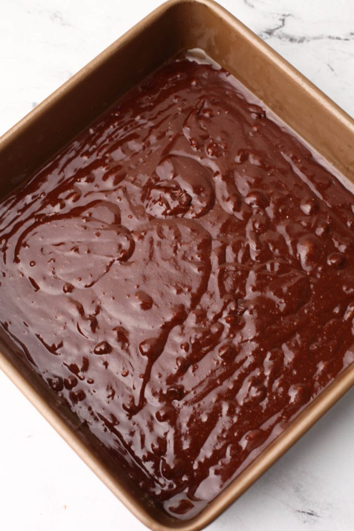 Vegan brownie batter poured into a square baking dish.